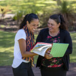 Building meaningful engagement with First Nations communities 5 Young aboriginal student talking to her tutor outdoors in the sun in Australia.